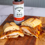 A bottle of Kinder's BBQ Sauce next to some food