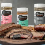 3 different bottles of Franklin Barbecue rubs behind BBQ meats